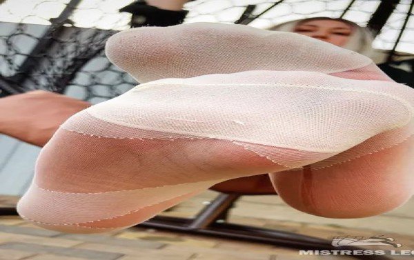 My beautiful feet in white tights are swing in a hanging chair outdoors to the sounds of barking dogs and crowing roosters